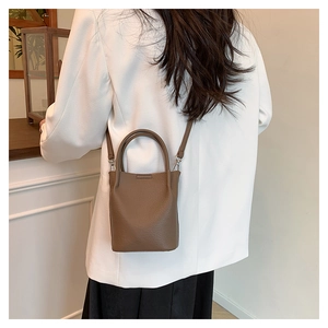 Brown lychee leather bucket bag showing back view on model with crossbody strap