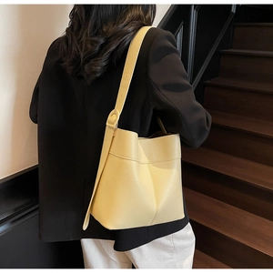 Litchi pattern yellow leather bucket bag worn by model showing actual size and fit