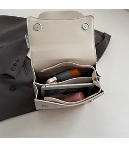 Detail view of spacious multi-compartment interior for cream leather handbag