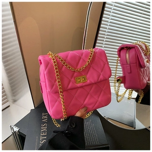 Close-up of pink quilted crossbody bag with gold chain strap and turn-lock closure