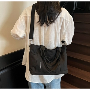 Detailed back view of a large black canvas tote bag with adjustable wide shoulder straps