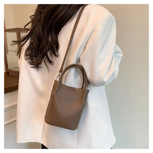 Detail of a brown lychee pattern leather bucket bag shown from a back perspective on model