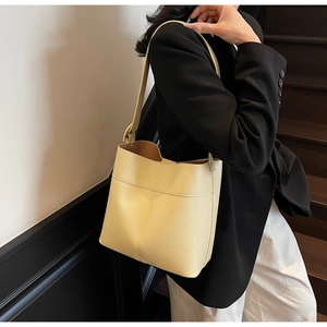 Detail of minimalist beige bucket bag with lychee texture leather and wide shoulder strap