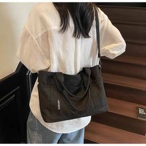 Detail of black canvas tote bag with adjustable shoulder strap and multiple pockets