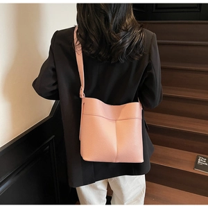 Detail of pink bucket bag with lychee texture and adjustable strap on a model