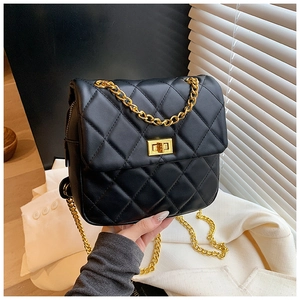 Detail of black quilted crossbody bag with golden chain strap and luxury turn-lock closure