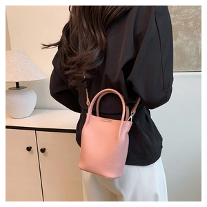 Detailed view of a pink lychee-grain mini bucket bag used as a stylish crossbody bag