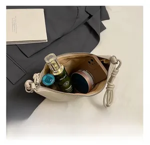 Top view showing interior capacity of beige crescent bag with phone and cosmetics