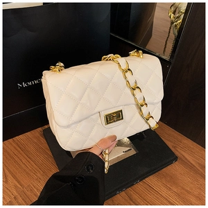 Detail of quilted leather crossbody bag with golden chain strap and turn-lock closure