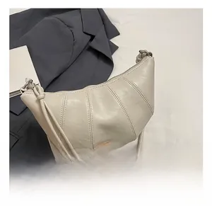 Detailed view of beige croissant shoulder bag with pleated leather texture and sleek strap