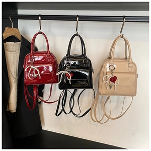 Detail view of mini glossy patent leather backpacks with pearl bows and heart charms