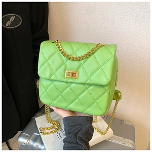 Detail of green quilted crossbody bag with gold chain strap and metallic lock closure