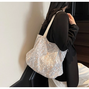 Dettaglio dell'elegante motivo in pizzo floreale bianco sulla borsa tote grande da donna