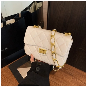 Macro shot of white quilted flap crossbody bag with gold metal lock and chain strap