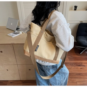 Detail of a beige canvas tote bag with brown straps styled for office and daily use