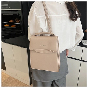 Detailed close-up of beige leather handbag with metal buckle and fashion lettering
