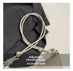 Detail shot of the adjustable knotted rope shoulder strap on a beige crescent bag