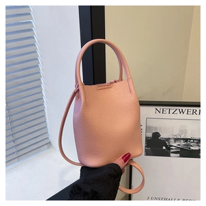 Detail of pink lychee grain leather bucket bag featuring a sturdy handle and slim shoulder strap