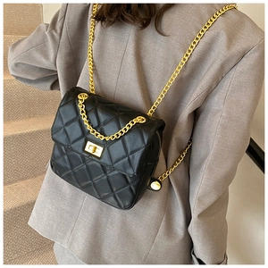 Detail of black quilted leather crossbody bag with golden chain and twist lock clasp