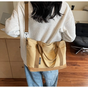 Rear view of a model wearing the large canvas tote bag with brown adjustable shoulder strap
