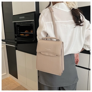 Detail of a beige fashion handbag with adjustable shoulder strap shown in a modern interior