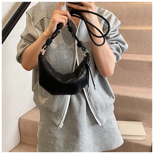 Detail of black croissant bag with stitched leather panels and a knotted braided strap