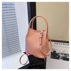 Detail of light pink bucket bag showing lychee grain leather texture and handle