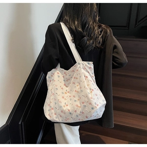 White floral canvas tote bag with a pink and blue pattern shown on a shoulder