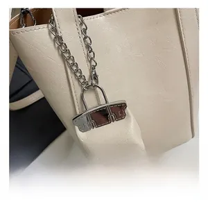 Detail shot of mini bag charm with silver chain on cream white pebbled leather handbag