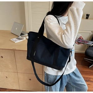 Detail of dark blue canvas tote bag with adjustable shoulder strap and black handles