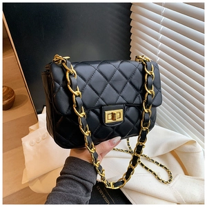 Close-up of black quilted leather crossbody bag with gold chain and twist lock clasp