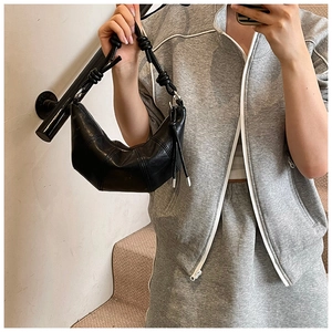 Detail of black croissant bag with decorative knots and vertical stitching seams