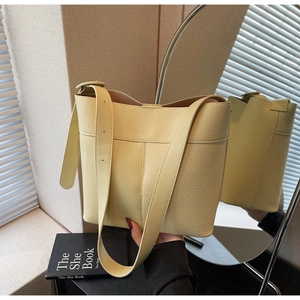 Detail view of cream yellow pebble leather bucket bag with wide adjustable strap
