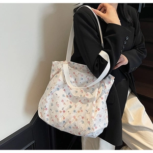 Borsa tote in tela a fiori indossata da modella con giacca nera ed elegante