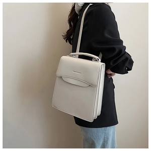 Close-up of white PU leather handbag with FASHION & BAG embossing and accordion pleats