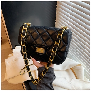 Detail of classic black quilted shoulder bag with gold metal lock and chain strap