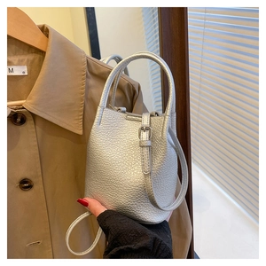 Detailed macro view of the silver bucket bag showing litchi grain leather and handle