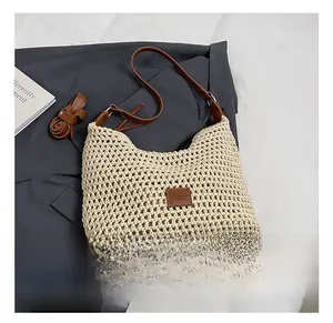 Detail of hand-woven crochet shoulder bag with brown leather strap and brand patch