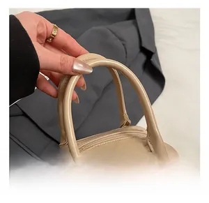 Close-up of beige patent leather handbag showing sleek top handle and silver metal rings