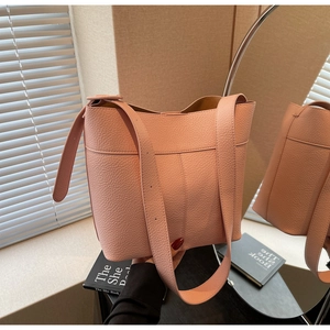 Pink lychee grain leather bucket bag with wide strap reflecting in a stylish mirror