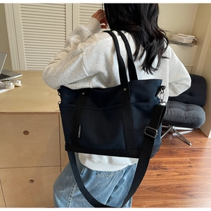 Model wearing a large canvas tote bag with adjustable shoulder strap in a cozy interior