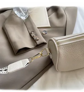 Close-up of cream barrel bag featuring lychee grain leather and gold-tone hardware detail