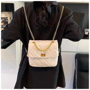 Rear view of model wearing a white quilted backpack with gold chain straps and twist lock