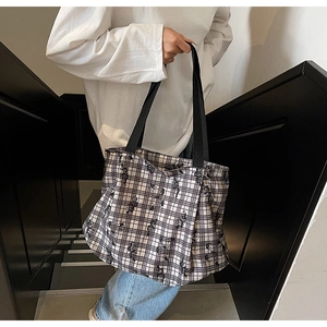 Detail of checkered canvas tote bag with black strap and artistic floral pattern