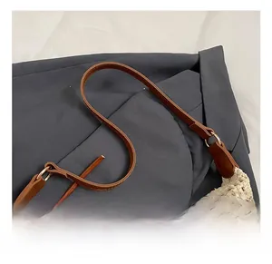 Detail of cream crochet tote bag featuring brown faux leather strap and golden metal ring