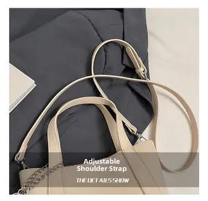 Detail view of the adjustable shoulder strap and silver chain on the beige tote bag
