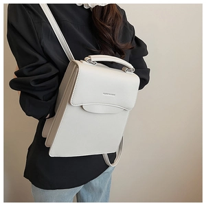 Close-up of minimalist off-white handbag featuring fashion lettering and silver hardware