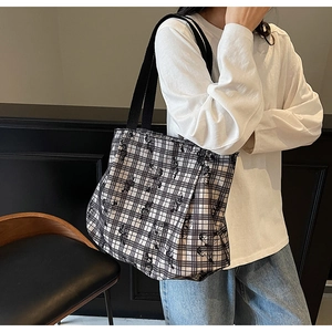 Detail of checkered canvas tote bag featuring black bow design and spacious interior