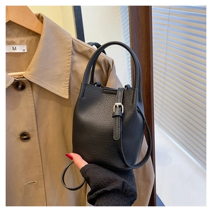Detail of black lychee grain leather bucket bag with silver buckle and dual handles