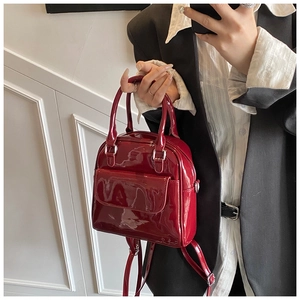 Deep burgundy patent leather mini backpack bag held by a model for a chic daily look